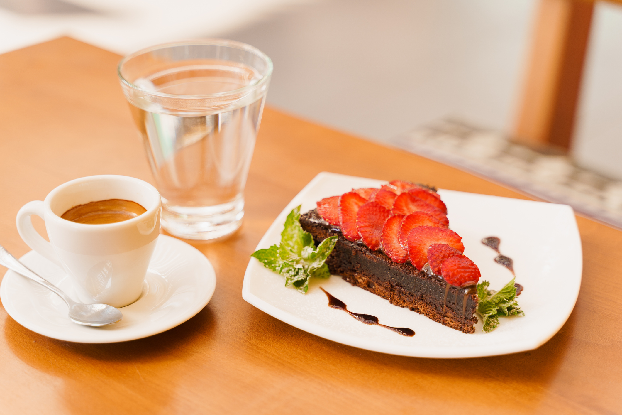 Chocolate cake, brownie with strawberries and mint, espresso, glass of water on a wooden table