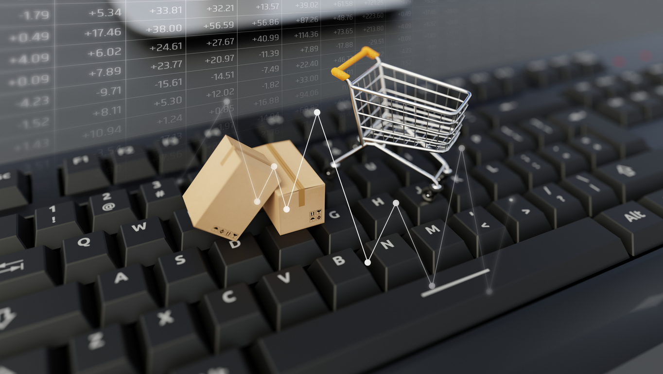 E-commerce. Shopping cart with cardboard boxes on keyboard.