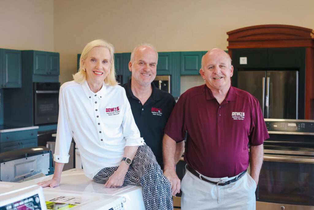 One woman and two men posed in a kitchen